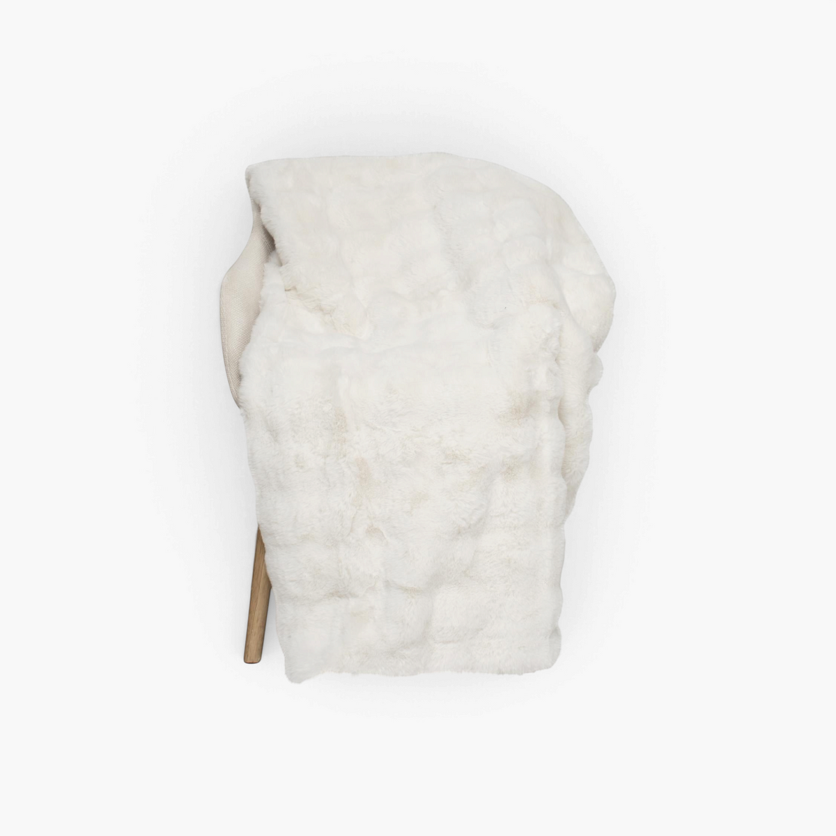 Lyckåsen Misty ivory faux fur throw blanket draped over a chair, featuring a soft and fluffy polyester texture.