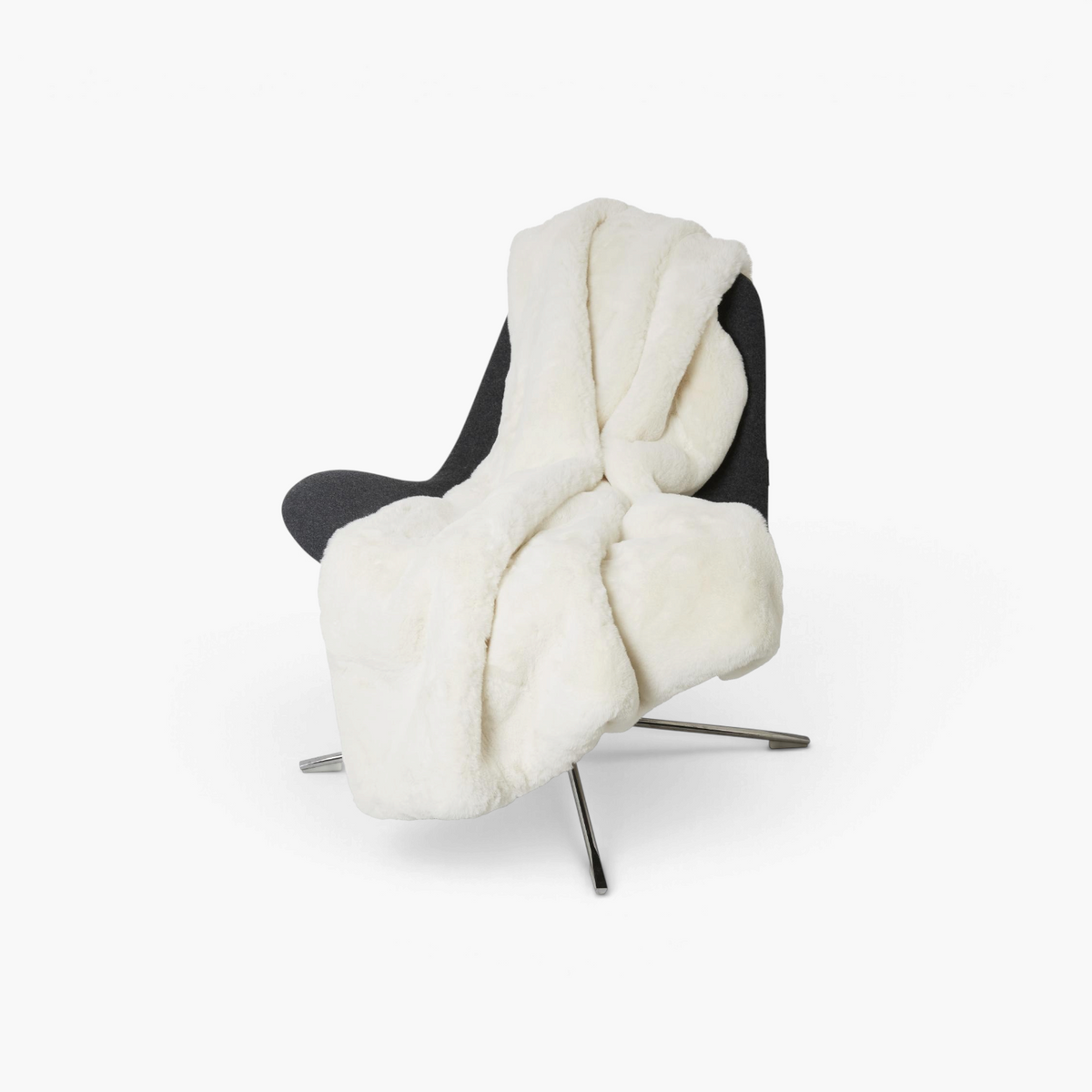 Lyckåsen ivory faux fur fluffy blanket draped over a modern dark grey chair