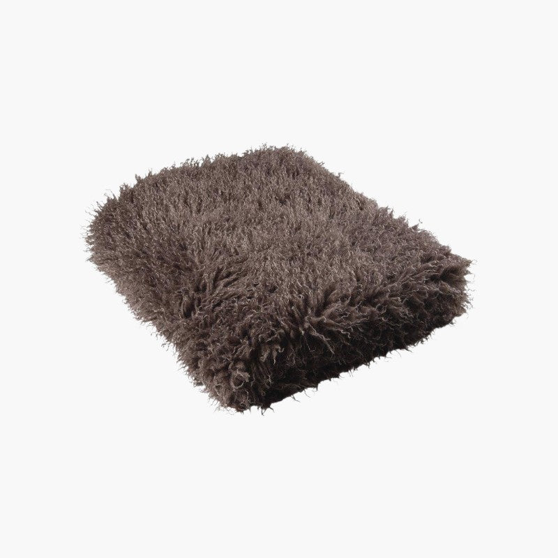 Lyckåsen brown faux fur throw blanket with a curly Tibetan sheepskin texture for a cozy and elegant home interior.