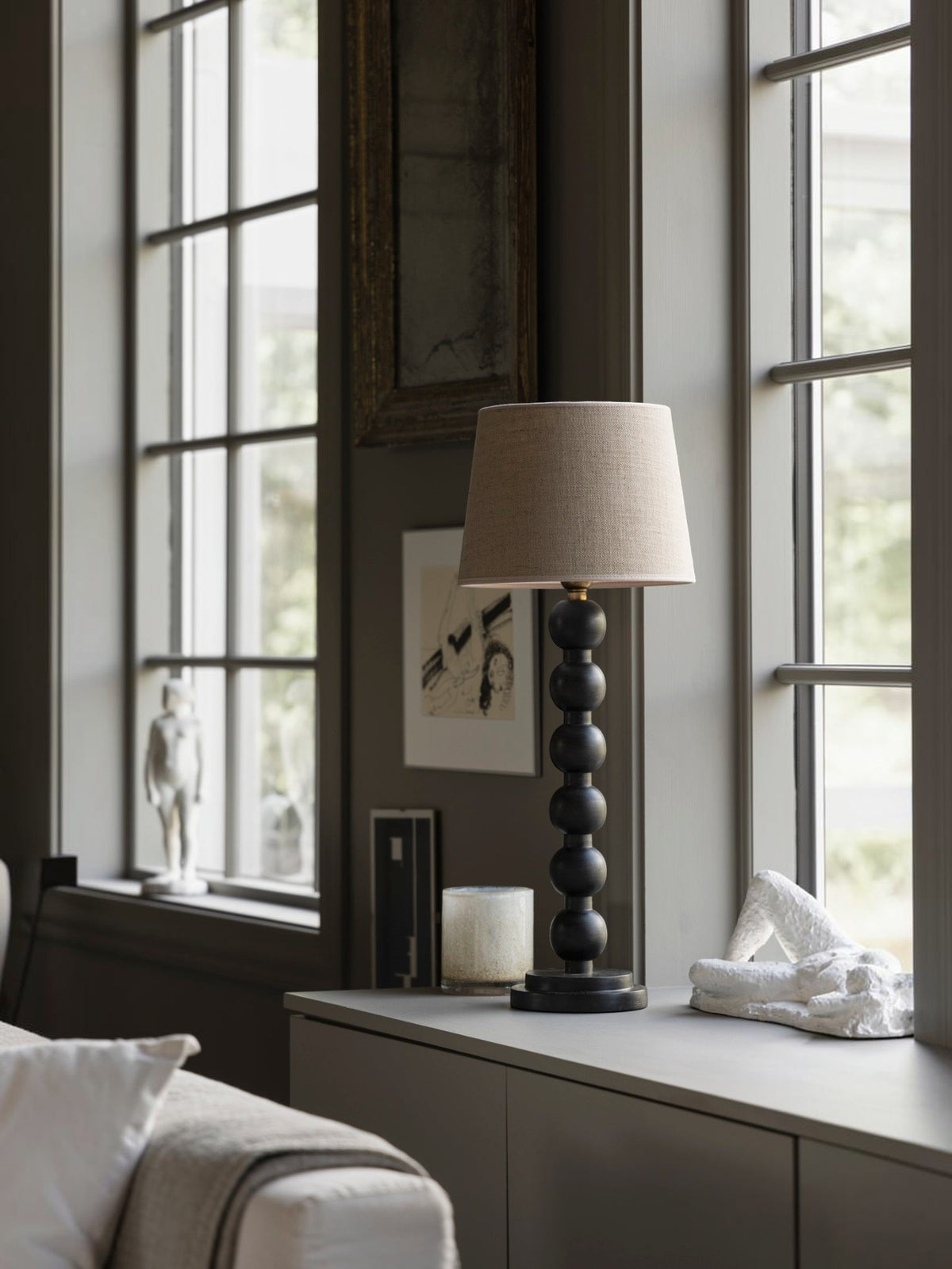 Lyckåsen Qvist 413 black wooden table lamp with a stacked sphere base and beige fabric shade on a bedside table.