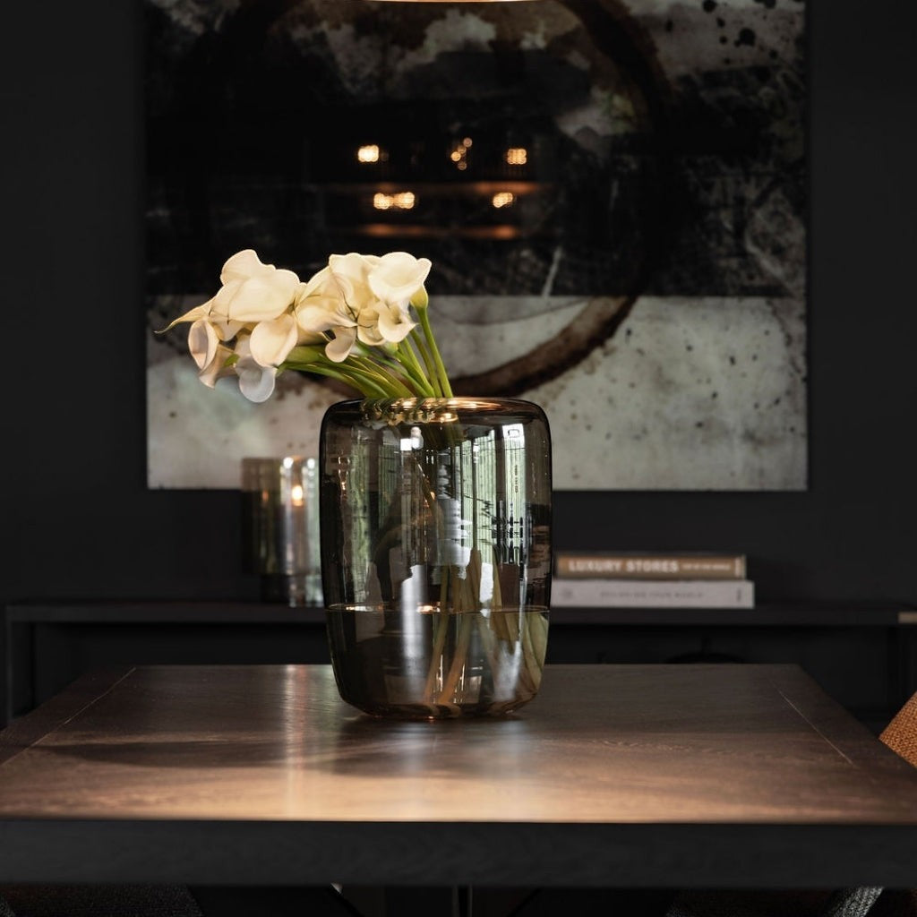 Lyckåsen Reef hand-blown glass vase in smoke brown with white flowers on a dark wooden table in a modern interior