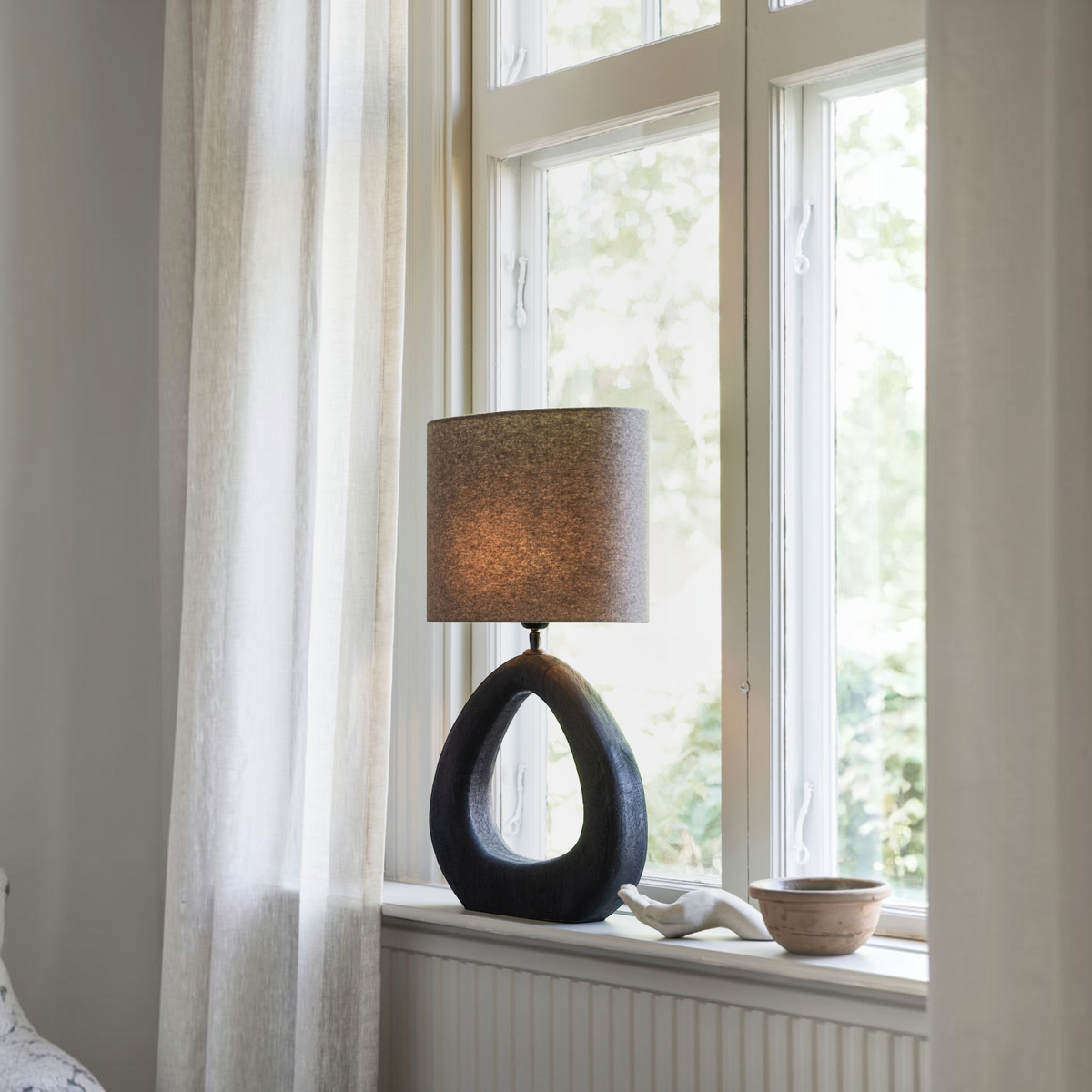 Lyckåsen Qvist modern oval lampshade in taupe fabric on a sculptural dark base placed on a window sill