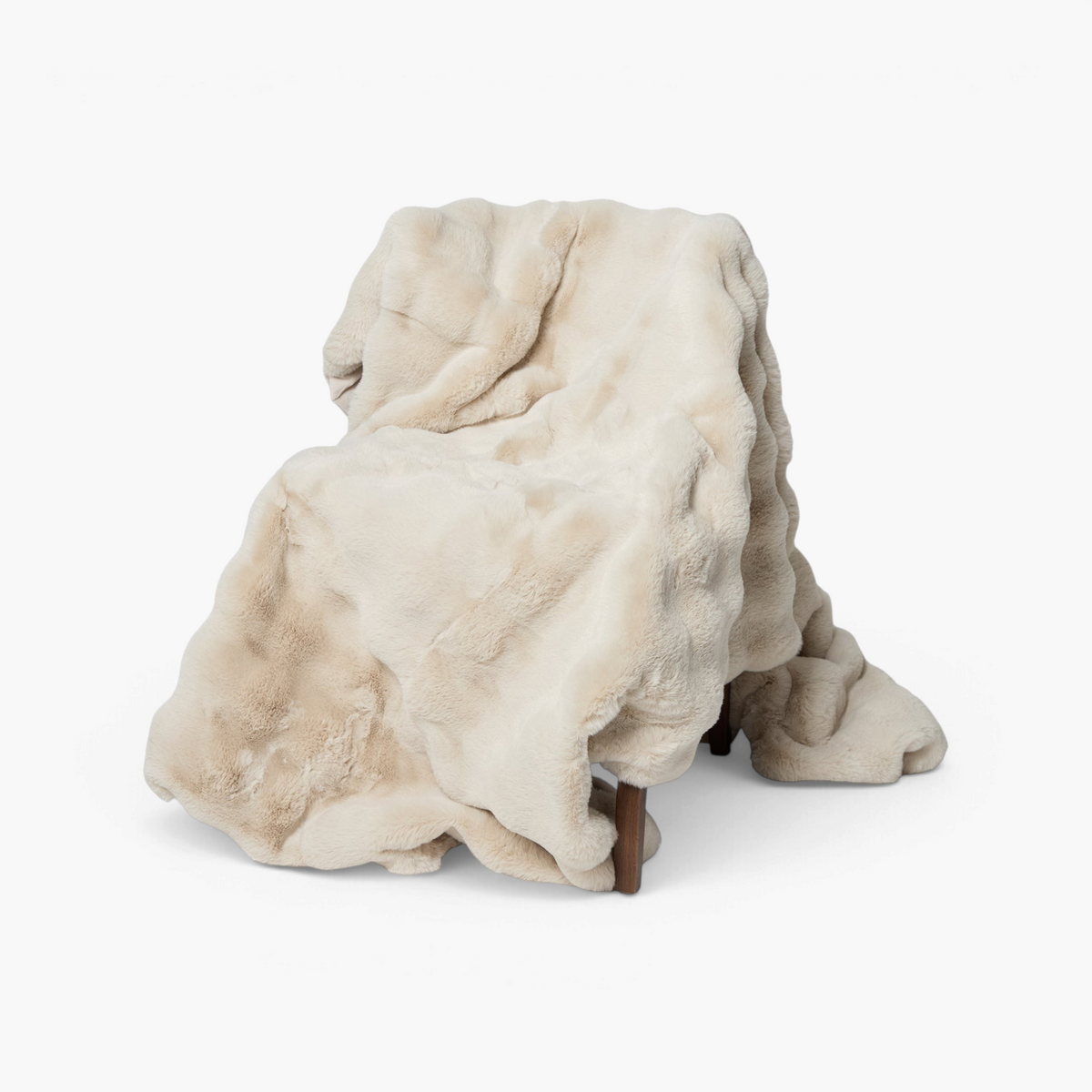 Lyckåsen Misty light beige faux fur throw blanket draped over a chair, featuring a soft and fluffy texture.
