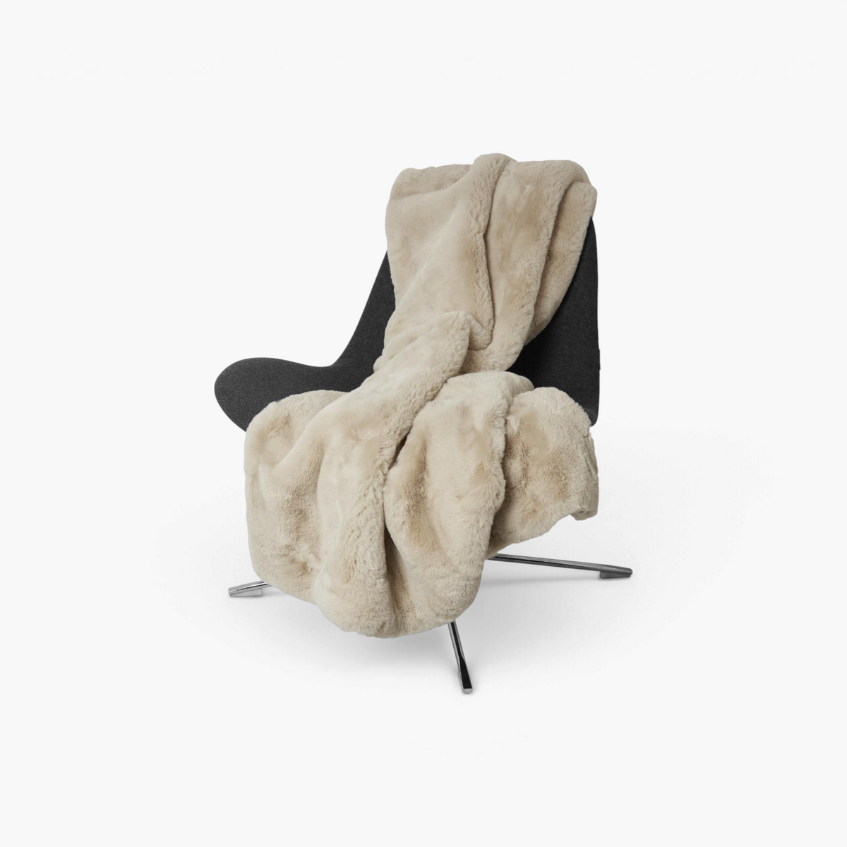Lyckåsen beige faux fur throw blanket draped over a modern dark grey chair, soft polyester texture.