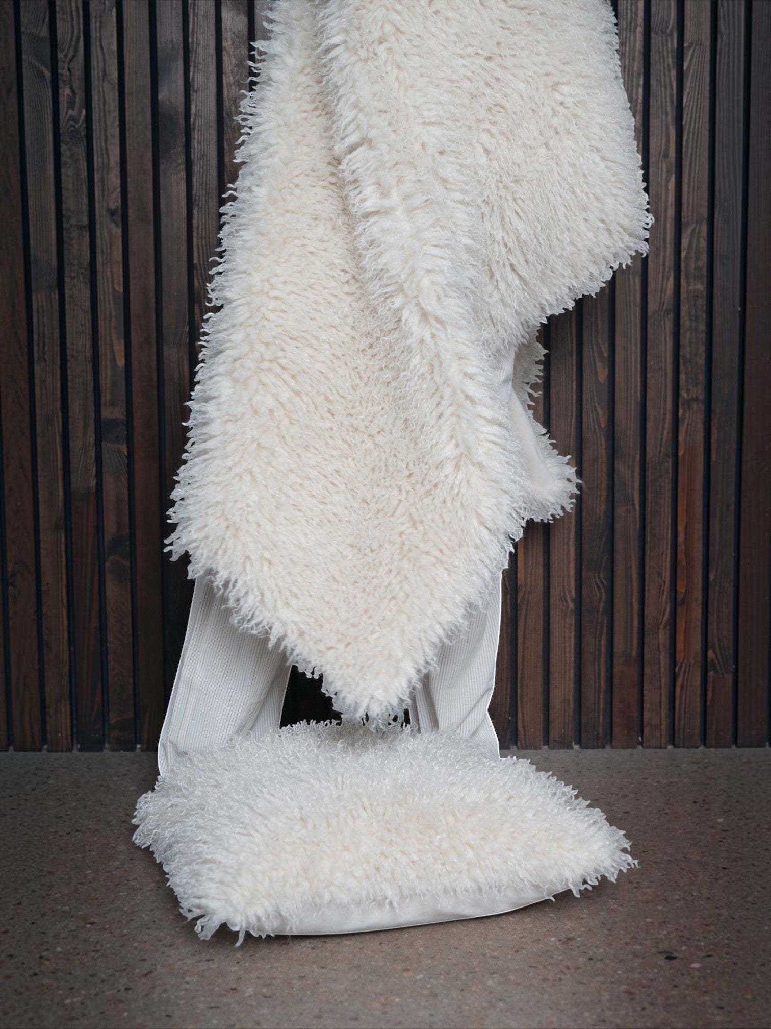 Lyckåsen offwhite faux sheepskin throw blanket with curly texture and soft suede-like backing draped over a chair