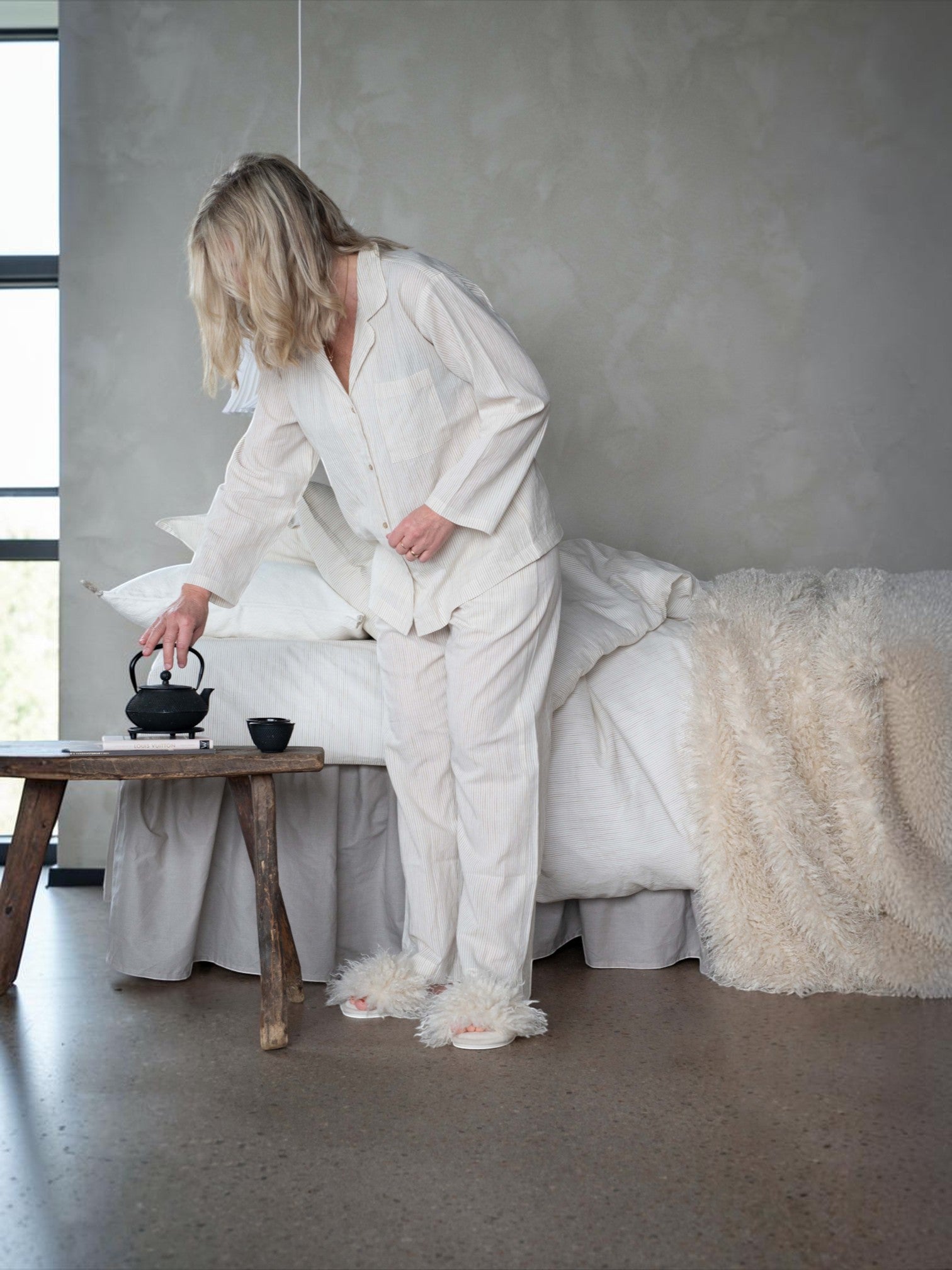 Lyckåsen offwhite faux sheepskin throw blanket draped over a bed in a cozy bedroom setting