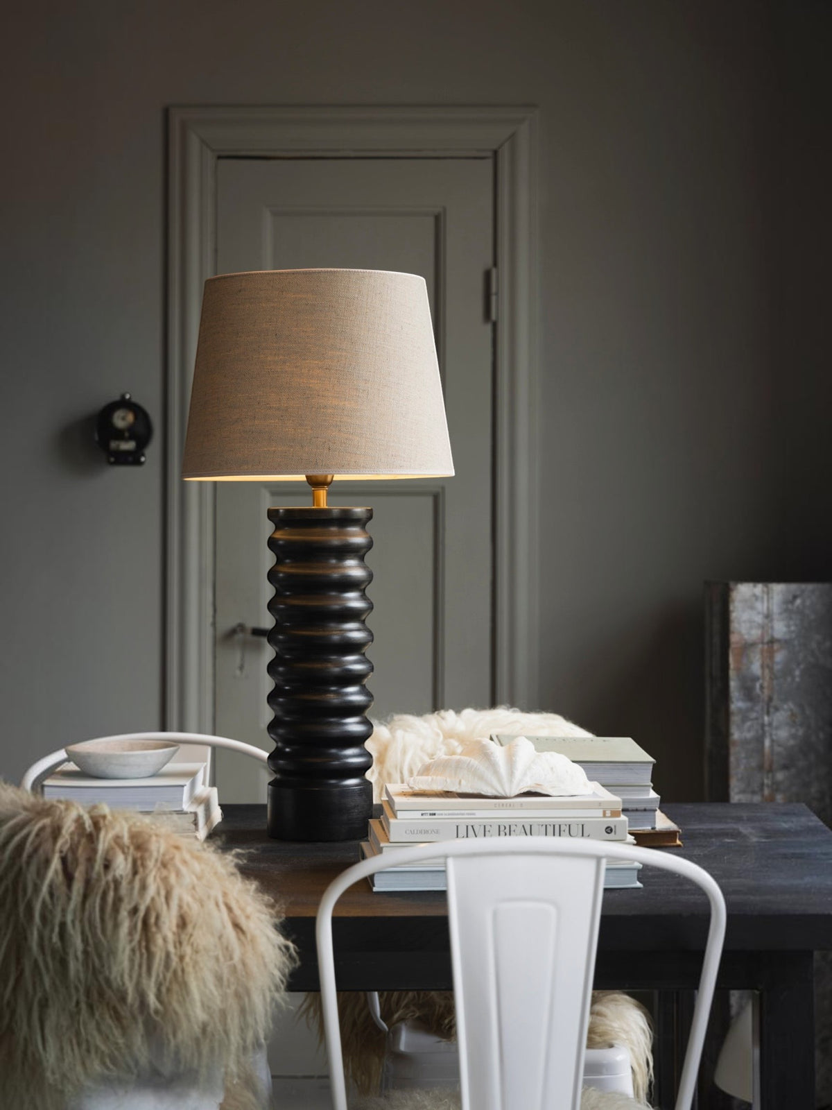 Lyckåsen Qvist 412 black wooden table lamp with a ribbed base and beige fabric shade on a dark dining table.